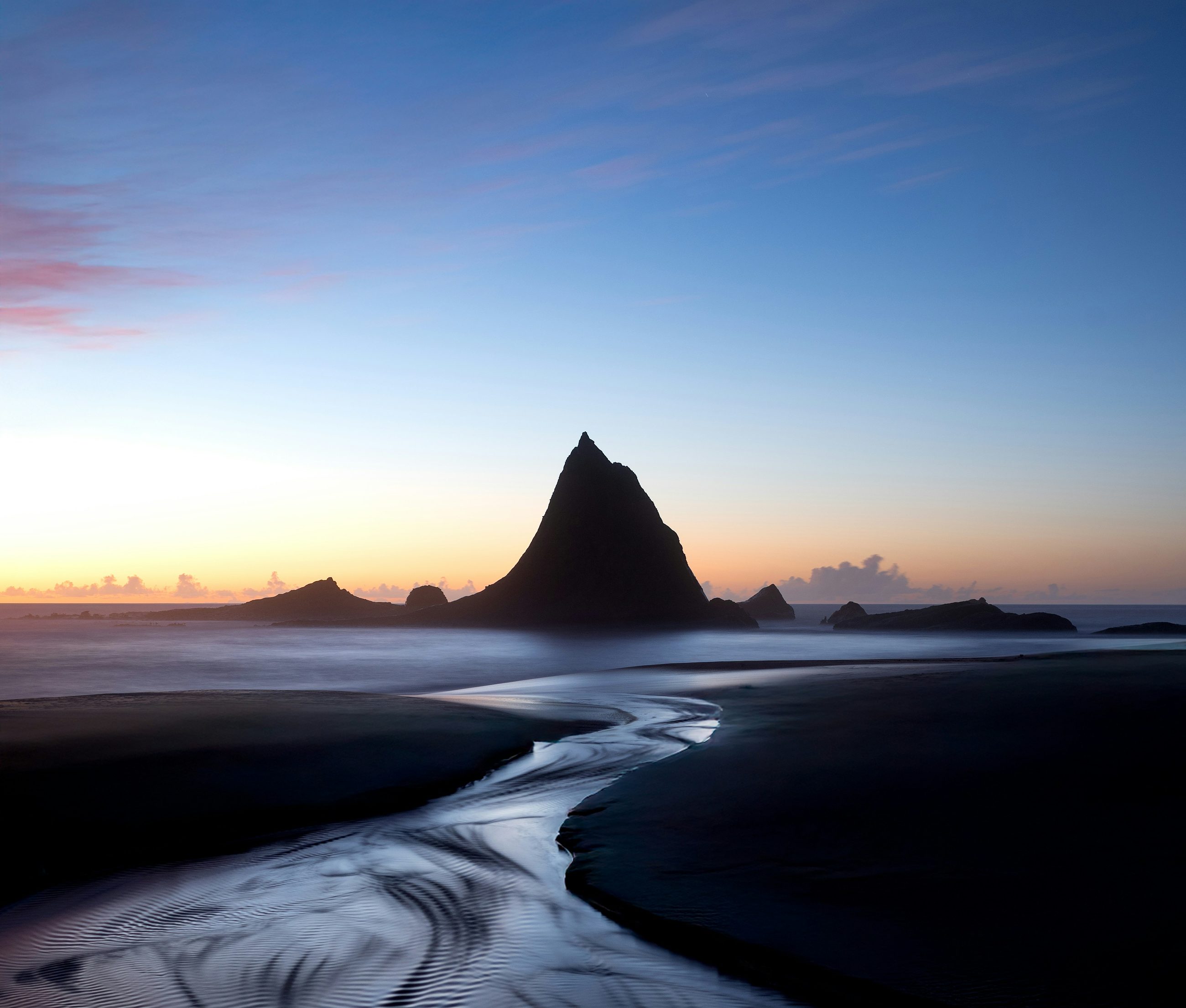 Martins Beach at blue hour: a pyramid sea stack silhouetted against an orange horizon